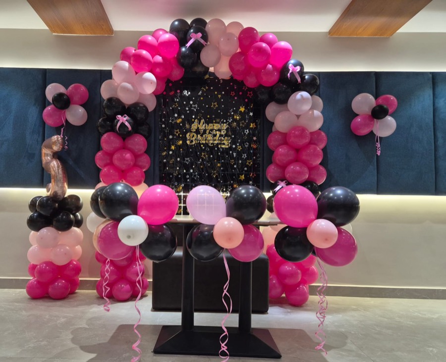 a balloon arch and birthday backdrop against the panelled wall