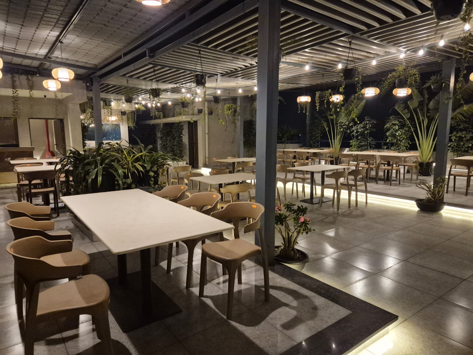 The open-air rooftop garden restaurant at night, with string lights and plants